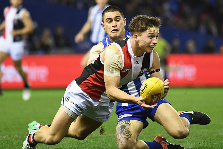 JACK BILLINGS of the Saints handballs whilst being tackled by Marley Williams during an AFL match between the North Melbourne Kangaroos and the St Kilda Saints at Etihad Stadium in Melbourne, Australia.