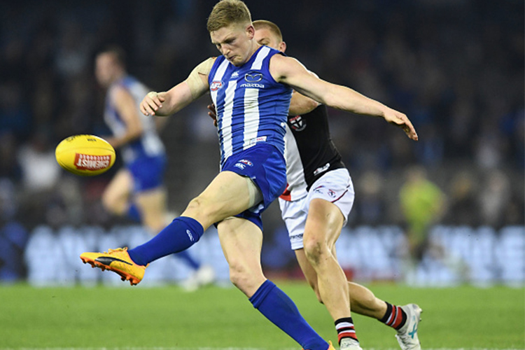 JACK ZIEBELL of the Kangaroos kicks whilst being tackled by Sebastian Ross of the Saints during the AFL match between the North Melbourne Kangaroos and the St Kilda Saints at Etihad Stadium in Melbourne, Australia.