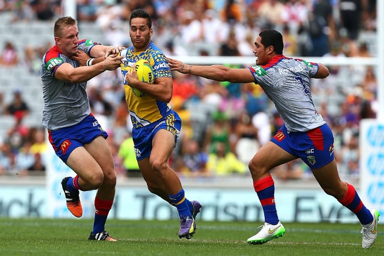 COREY NORMAN of the Eels beats the tackles of Jack Stockwell and Sione Mata'utia-Leifi of the Knights during the match between the Parramatta Eels and the Newcastle Knights at Eden Park in Auckland, New Zealand.