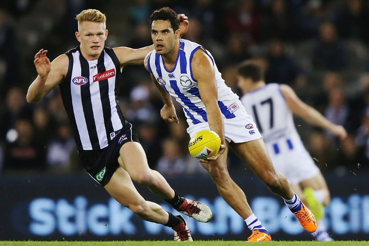 DANIEL WELLS of the Kangaroos handballs away from ADAM TRELOAR of the Magpies during the AFL match between the Collingwood Magpies and the North Melbourne Kangaroos at Etihad Stadium in Melbourne, Australia.
