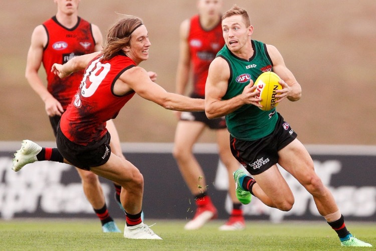 DEVON SMITH of the Bombers runs with the ball under pressure from Kobe Mutch of the Bombers during an Essendon Bombers AFL training session at the Essendon Football Club in Melbourne, Australia.