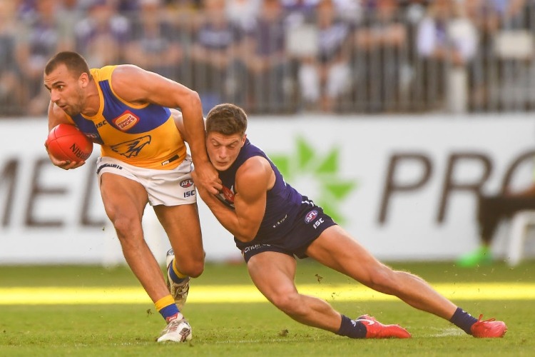DOM SHEED of the Eagles is tackled by DARCY TUCKER of the Dockers during the 2018 AFL match between the Fremantle Dockers and the West Coast Eagles at Optus Stadium in Perth, Australia.