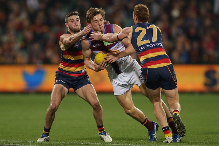 HARRIS ANDREWS of the Lions is tackled by Brad Crouch and Tom Lynch of the Crows during the 2016 AFL match between the Adelaide Crows and the Brisbane Lions at Adelaide Oval in Adelaide, Australia.