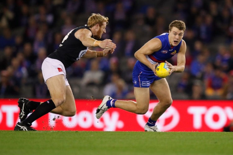 JACK MACRAE of the Bulldogsin action ahead of Andrew Phillips of the Blues during the AFL match between the Western Bulldogs and the Carlton Blues at Etihad Stadium in Melbourne, Australia.