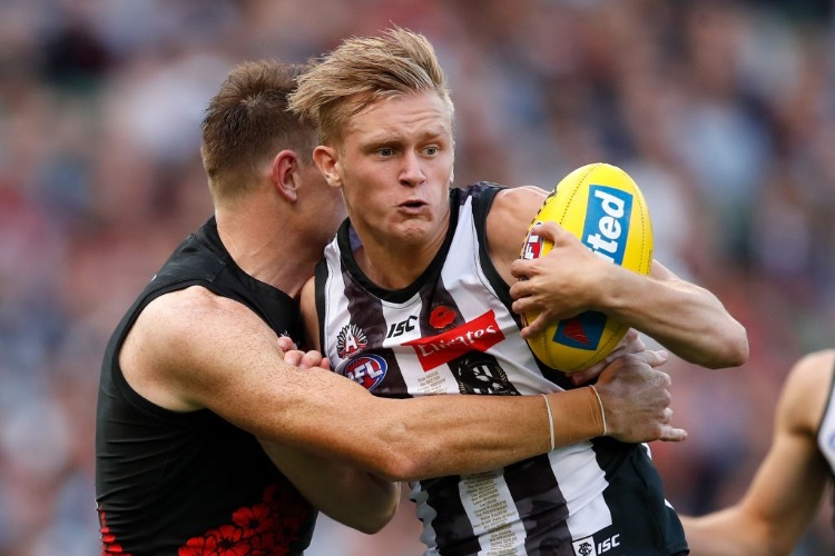 JAIDYN STEPHENSON of the Magpies is tackled by Brendon Goddard of the Bombers during the 2018 AFL ANZAC Day match between the Collingwood Magpies and the Essendon Bombers at the MCG in Melbourne, Australia.