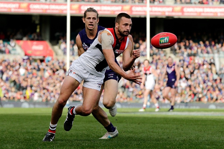 JARRYN GEARY of the Saints handpasses the ball under pressure from Nat Fyfe of the Dockers during an AFL match at Domain Stadium in Perth, Australia.