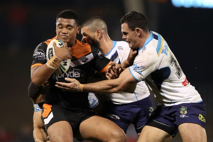 MOSES SULI of the Tigers is tackled during the NRL match between the Wests Tigers and the Gold Coast Titans at Campbelltown Sports Stadium in Sydney, Australia.