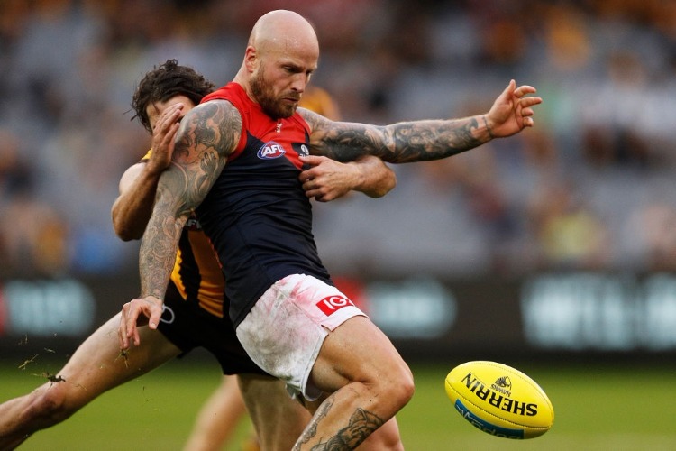 NATHAN JONES of the Demons kicks the ball whilst being tackled by Isaac Smith of the Hawks during the AFL match between the Hawthorn Hawks and the Melbourne Demons at MCG in Melbourne, Australia.