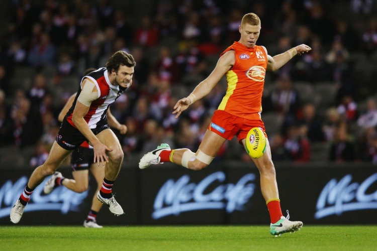 PETER WRIGHT of the Suns kicks the ball at goal from DYLAN ROBERTON of the Saints during the AFL match between the St Kilda Saints and the Gold Coast Suns at Etihad Stadium in Melbourne, Australia.