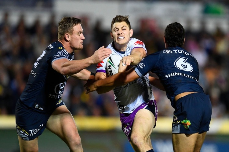 RYLEY JACKS of the Storm is tackled by Coen Hess and Te Maire Martin of the Cowboys during the NRL match between the North Queensland Cowboys and the Melbourne Storm at 1300SMILES Stadium in Townsville, Australia.
