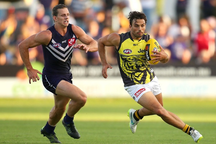 SAM LLOYD of the Tigers avoids being tackled by NATHAN FYFE of the Dockers during the AFL NAB Challenge match between the Fremantle Dockers and the Richmond Tigers at Rushton Park in Mandurah, Australia.