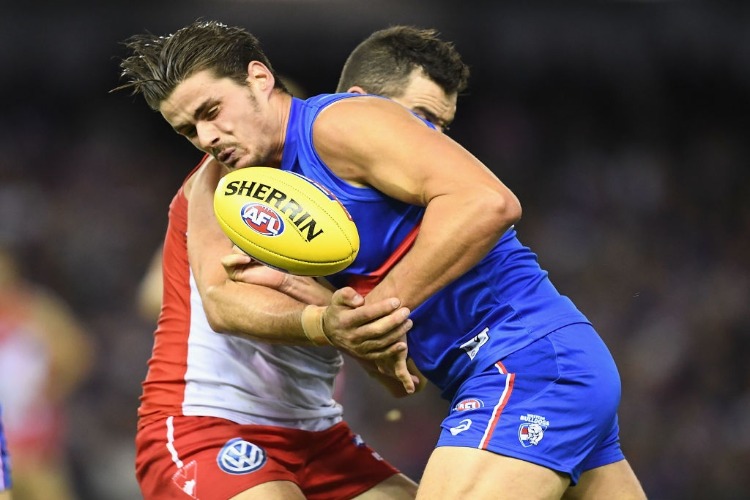 TOM BOYD of the Bulldogs handballs whilst being tackled during the AFL match between the Western Bulldogs and the Sydney Swans at Etihad Stadium in Melbourne, Australia.