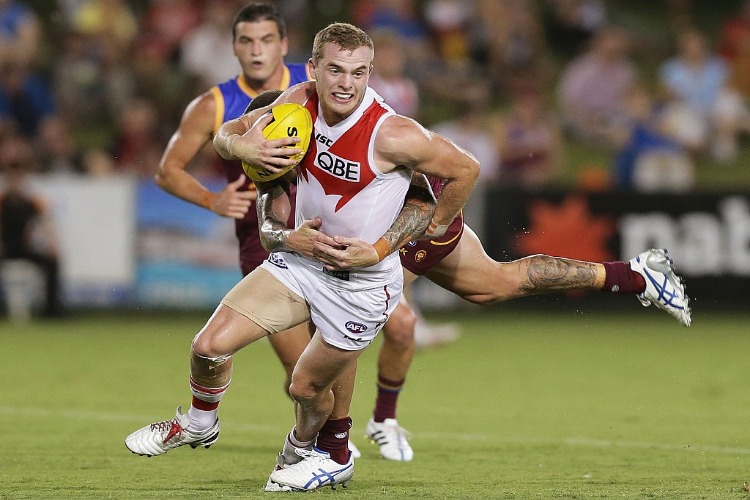 TOM MITCHELL of the Swans is tackled by Claye Beams of the Lions during the NAB Challenge AFL match between the Sydney Swans and the Brisbane Lions at Coffs Harbour International Stadium in Coffs Harbour, Australia.