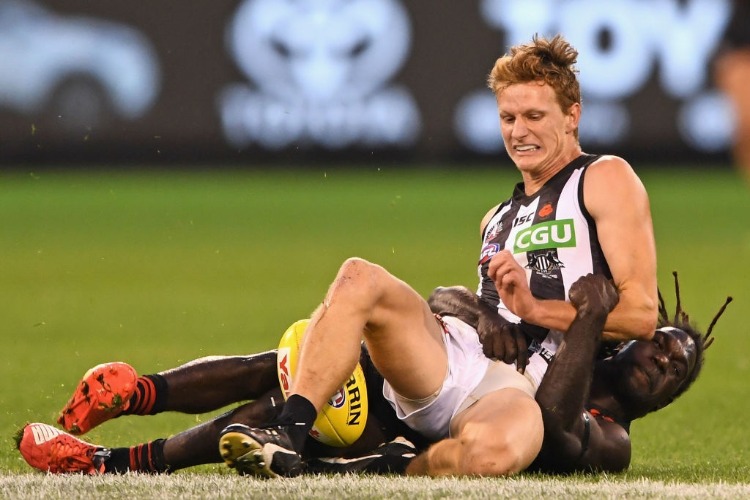 WILL HOSKIN-ELLIOTT of the Magpies kicks whilst being tackled by Anthony McDonald-Tipungwuti of the Bombers during the AFL match between the Essendon Bombers and the Collingwood Magpies in Melbourne, Australia.
