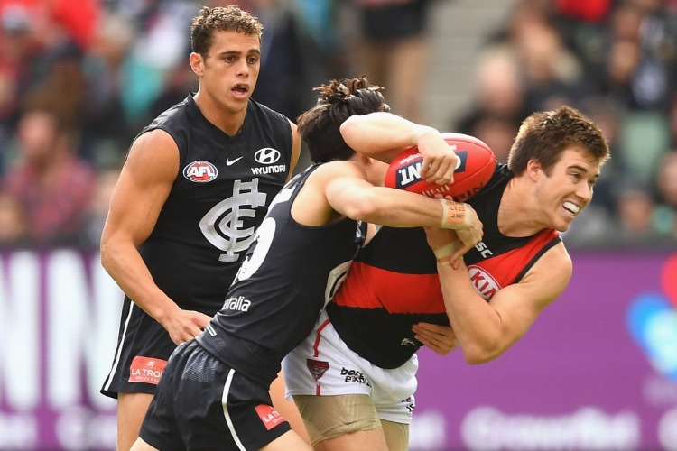 ZACH MERRETT of the Bombers is tackled by Zac Fisher of the Blues during the AFL match between the Carlton Blues and the Essendon Bombers at MCG in Melbourne, Australia.