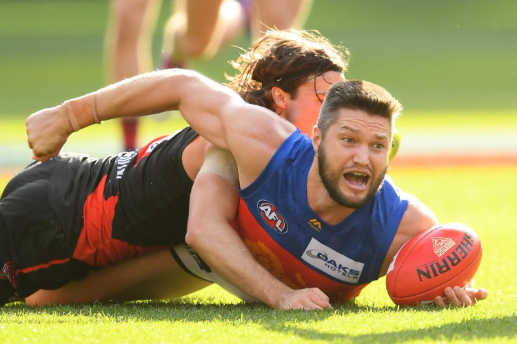 STEFAN MARTIN of the Lions handballs whilst being tackled during the AFL match between the Essendon Bombers and the Brisbane Lions at MCG in Melbourne, Australia.
