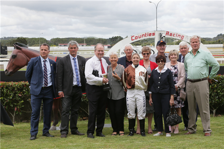 Philip Brown and his wife Catherine pose with the trophy for the Listed Haunui Farm Counties Bowl (1100m) along with Counties Racing Club officials and members of the syndicate that race talented filly Levante