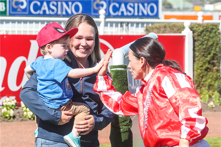 Sam Wynne shares a “high five” with trainer Matthew Pitman’s son Benji after the win by All About Magic