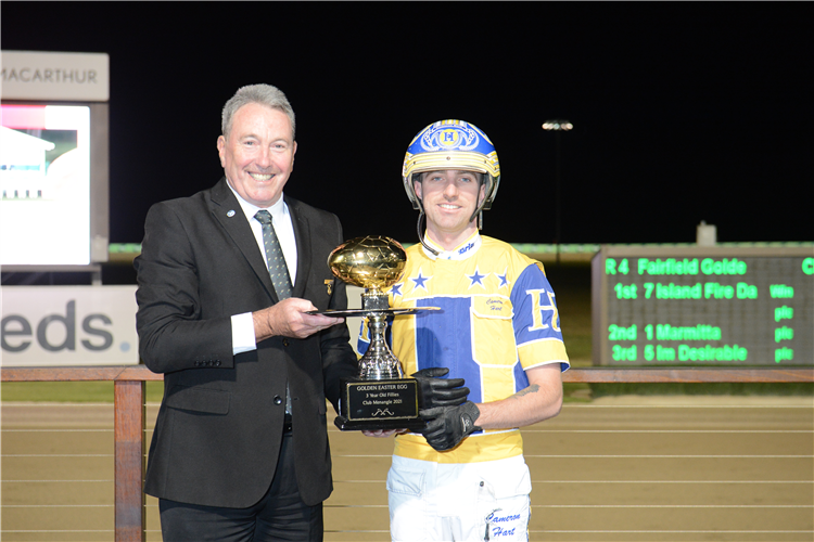 Club Menangle Chairman Mr Robert Marshall presents the 2021 Fairfield Golden Easter Egg (Group 3) trophy to driver Cameron Hart after he partnered Island Fire Dance to victory for trainer Jason Grimson.