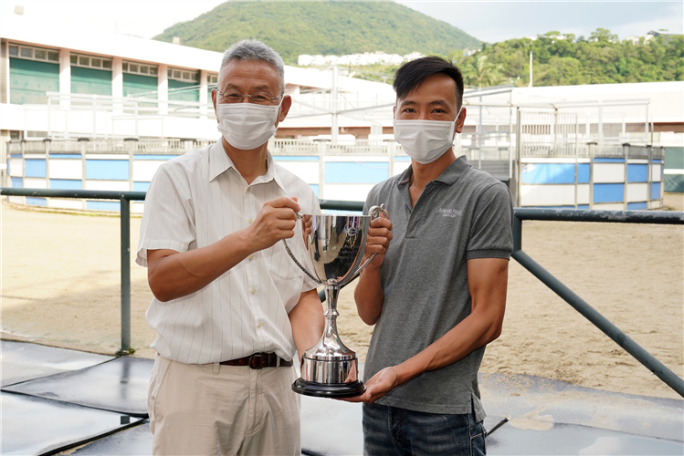 Samson Lau (left), Training Manager/Safety Manager, Racing Talent Training Centre, presents the stable prize to Wong Pui Kan (right), Work Rider of the Caspar Fownes stable.