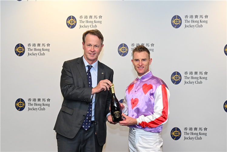 Zac Purton receives a commemorative bottle of champagne from Andrew Harding, Executive Director, Racing, The Hong Kong Jockey Club.