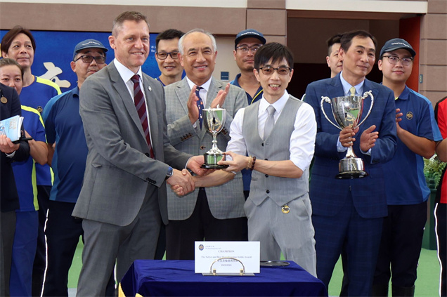 香港賽馬會賽馬營運總監魏德(左) 將「最安全及整潔馬房獎」的馬房獎項頒予鄭俊偉馬房的助理練馬師梁明偉(右)