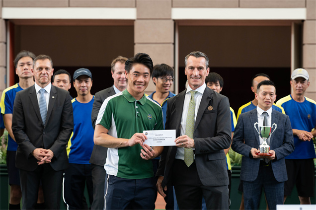 香港賽馬會賽馬日營運、跑道及賽馬設施部主管暨職業安全委員會主席（賽事執行部）夏俊思（右），將「最安全及整潔馬房獎」的馬房獎項頒予告東尼馬房的員工代表