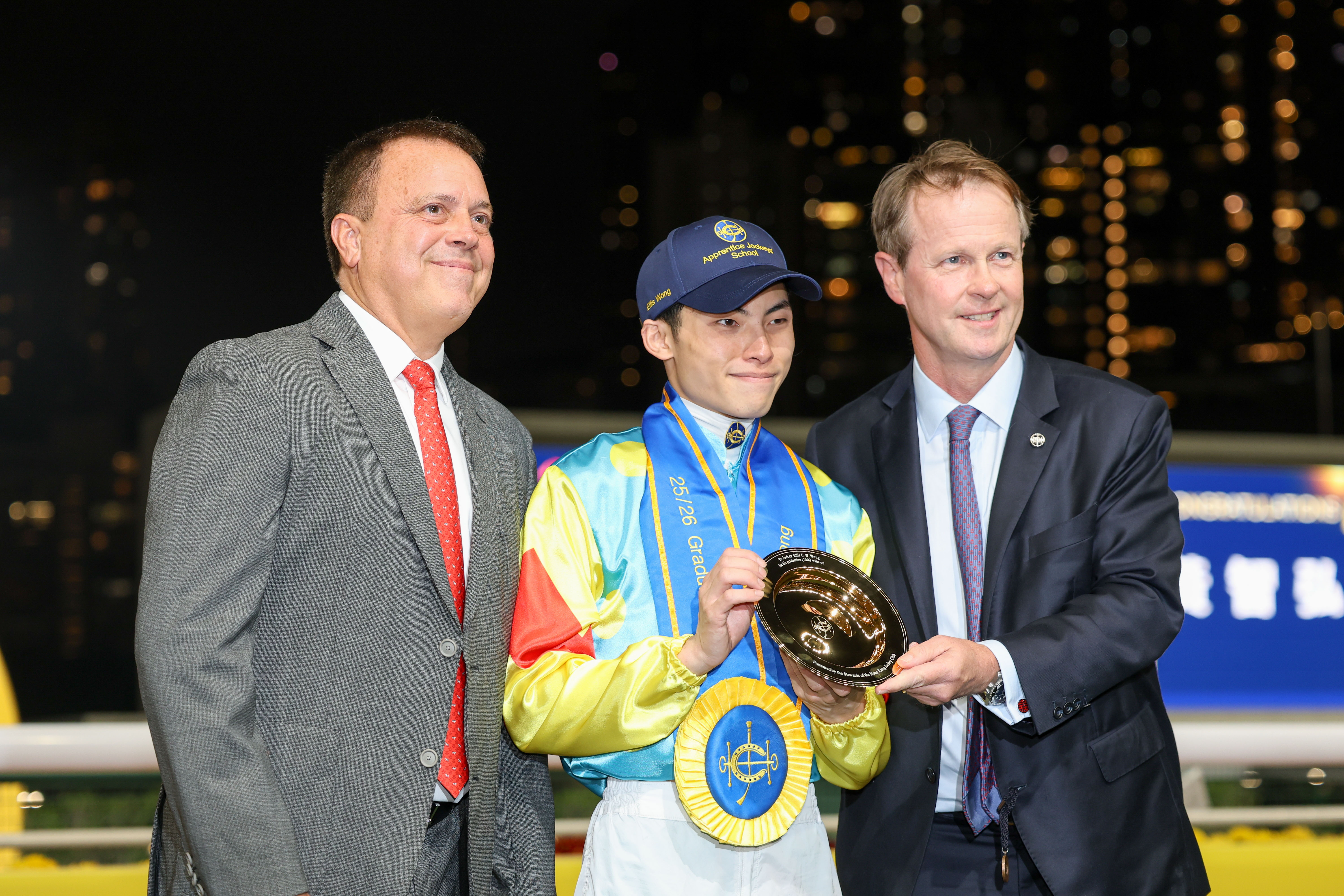 黃智弘在畢業禮上從香港賽馬會賽馬事務執行總監夏定安手中接過紀念銀碟