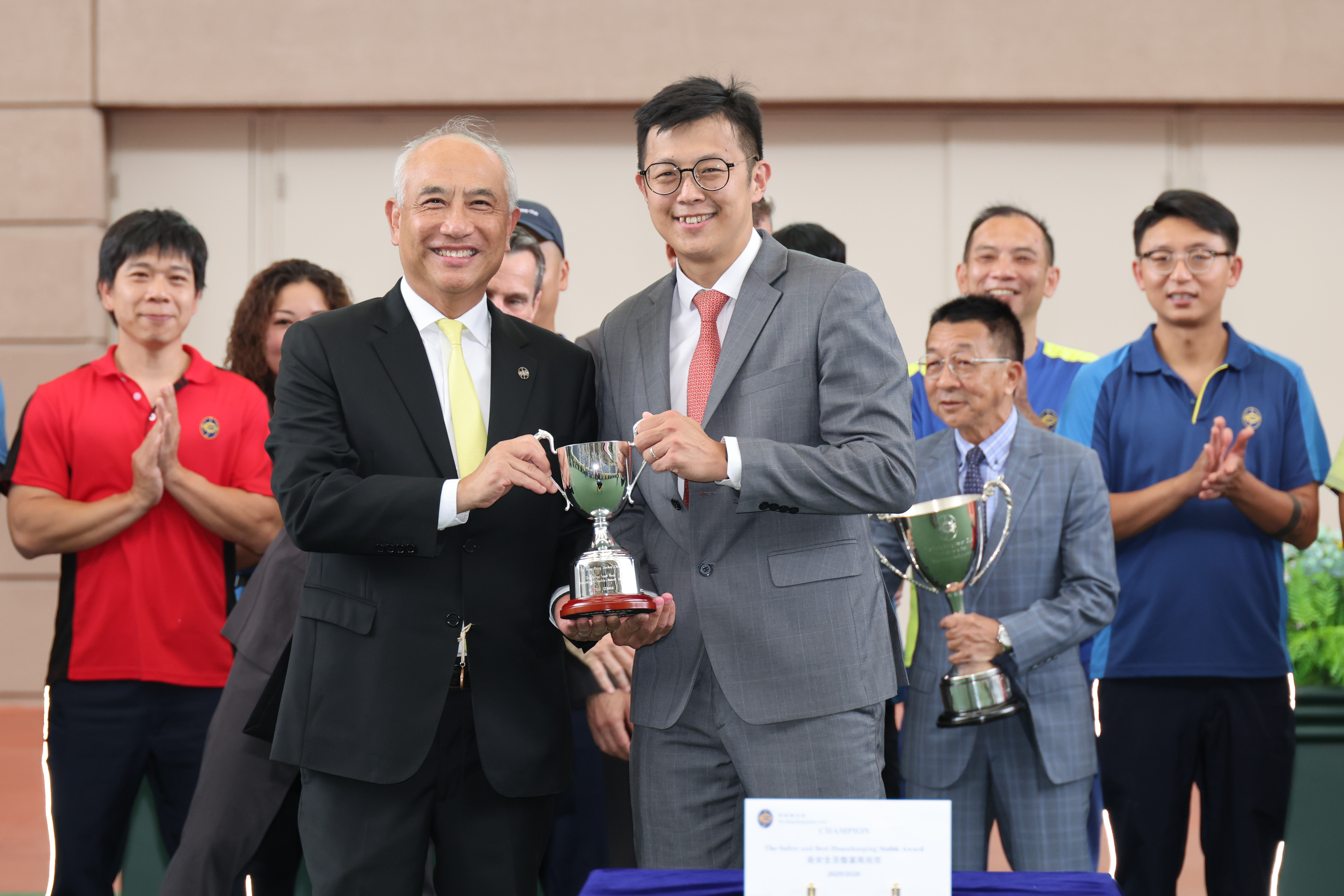 香港賽馬會兩地馬房營運部主管鄭奇龍（左）將「最安全及整潔馬房獎」的馬房獎項頒予徐雨石馬房的助理練馬師戴兆麟（右）