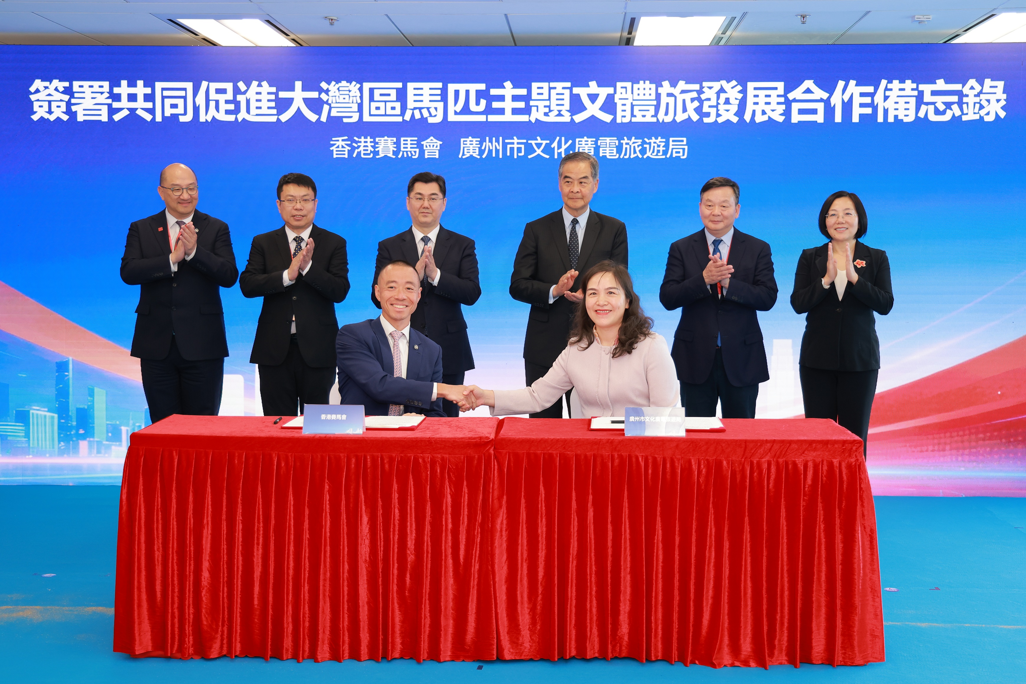 在全國政協副主席梁振英（後排右三）、廣州市人民政府市長孫志洋（後排左三）、中央人民政府駐香港特別行政區聯絡辦公室經濟部副部長呂峰（後排左二）、廣東省大灣區辦常務副主任朱偉（後排右二）、廣州市文化廣電旅遊局局長劉瑜梅（後排右一）及香港賽馬會公司事務執行總監譚志源（後排左一）見證下，香港賽馬會內地事務部主管陳岳鵬（前排左）及廣州市文化廣電旅遊局黨組成員、總工程師李若嵐（前排右）代表簽署合作備忘錄，共同推動透過「兩地三馬場」促進大灣區馬匹主題文體旅發展